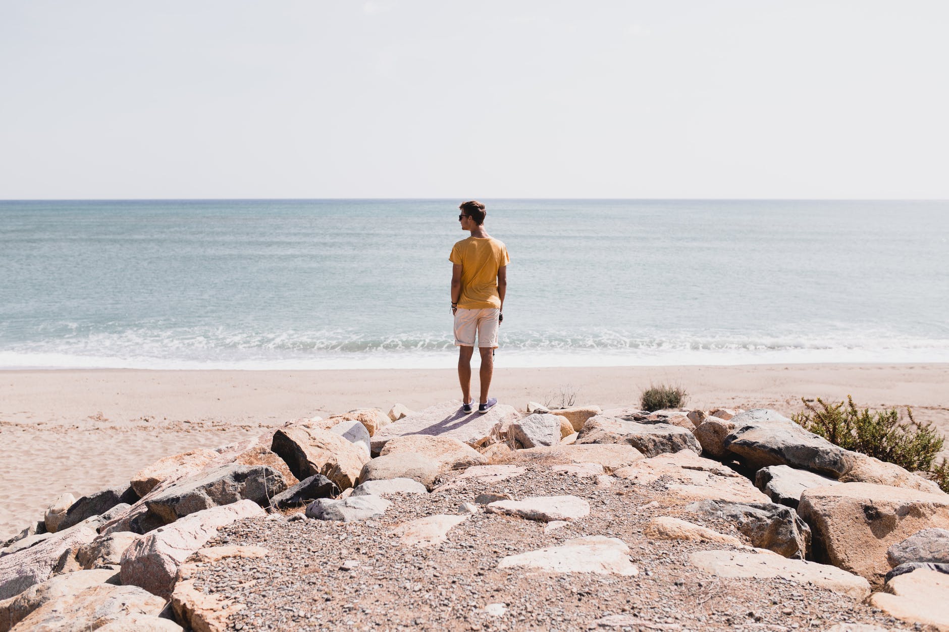 man in brown shorts standing on rocky shore