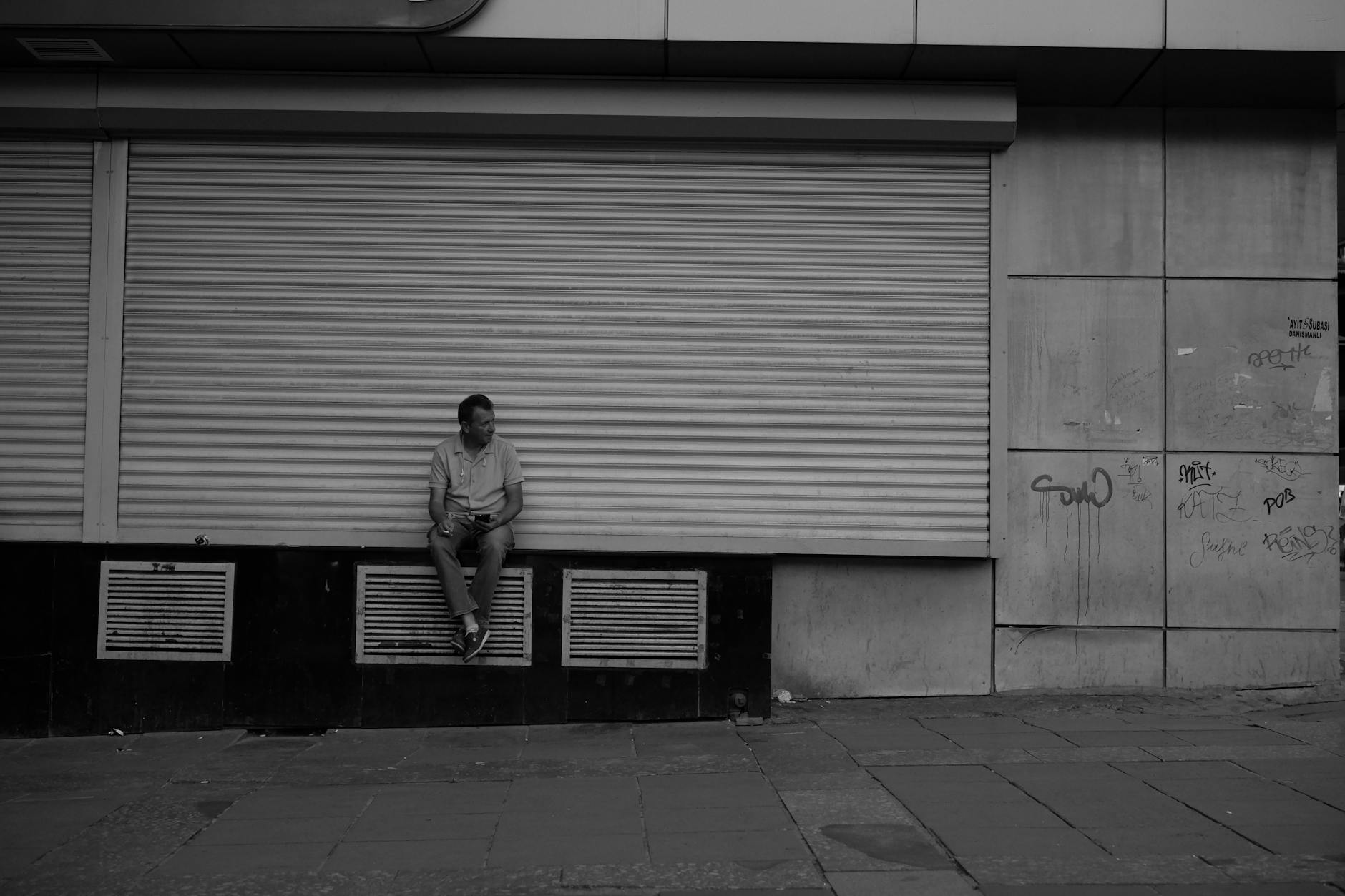 man sitting in front of closed store