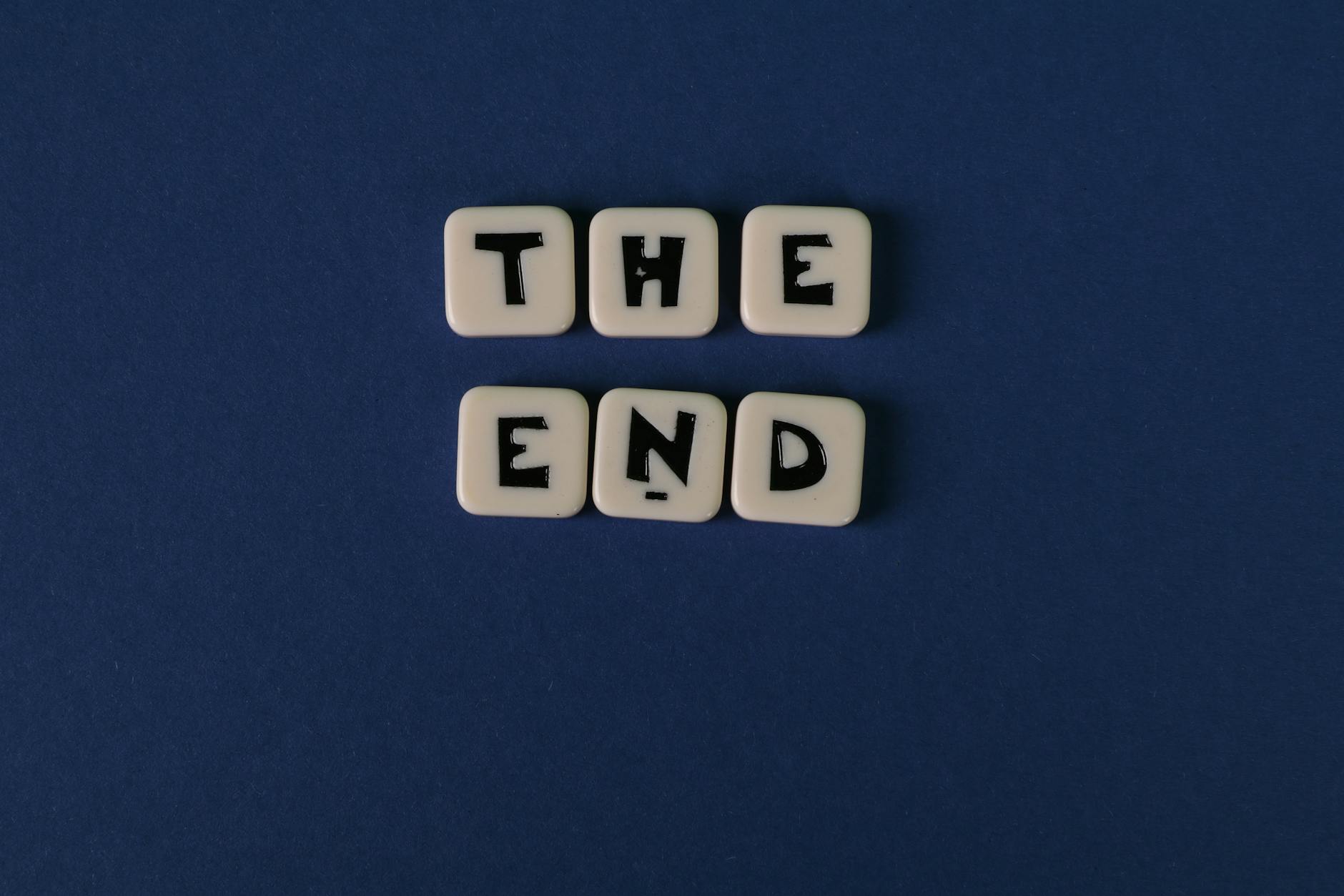 scrabble tiles forming the words the end on blue background